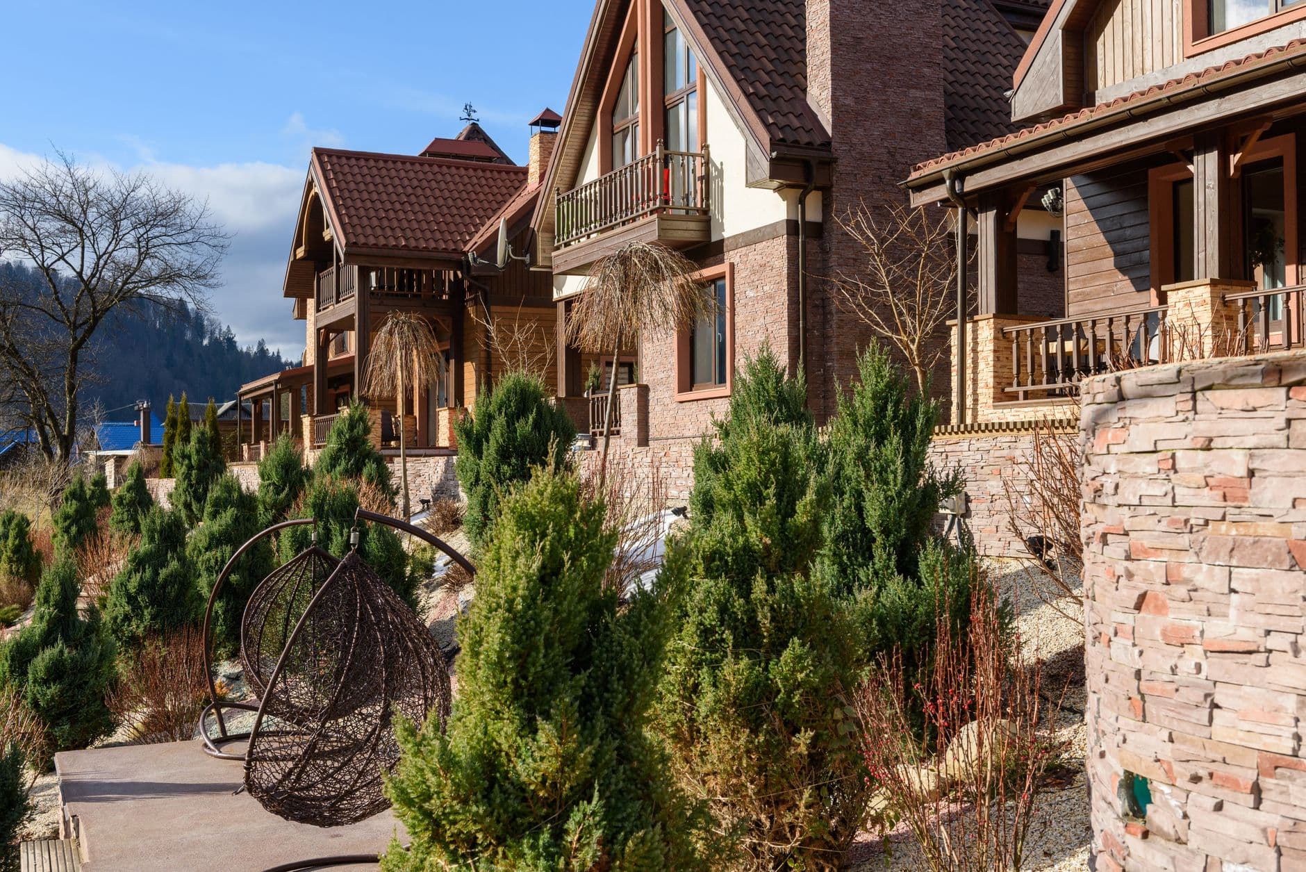 Charming mountain chalets with rustic facades amidst lush greenery in a serene outdoor setting.